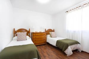 two beds in a bedroom with white walls and wood floors at Casa Carolina in Puntillo del Sol