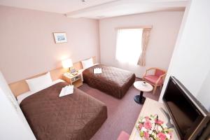 a hotel room with two beds and a flat screen tv at Hotel Unisite Sendai in Sendai