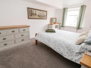 a bedroom with a bed and a dresser and a window at Bluebell Cottage in Ormskirk