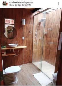 a bathroom with a shower with a toilet and a sink at Chalé Mirante da Pedra in Serra de São Bento