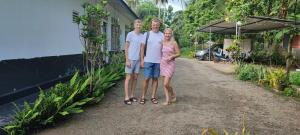 grupa trzech osób stojących obok domu w obiekcie Paradise inn w mieście Kamburagalla