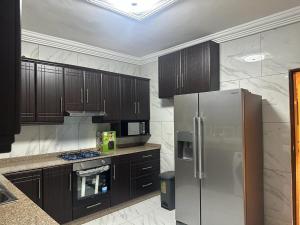 a kitchen with wooden cabinets and a stainless steel refrigerator at After 5 Apartment 2 3 spacious en-suite bedrooms in Freetown
