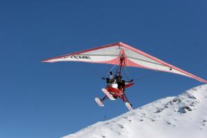 a man flying a glider over a snow covered mountain at Les Balcons PROCHE PARC NATIONAL VANOISE appartements 2 pieces 8 pers in Termignon