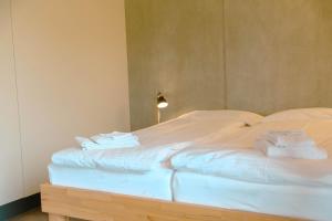 Una cama blanca con toallas encima. en Niesen, en Spiez