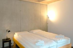 una cama con sábanas blancas y una lámpara en una habitación en Niesen, en Spiez