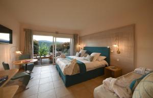 a hotel room with two beds and a large window at Hôtel Alivi Di Santa Giulia in Porto-Vecchio