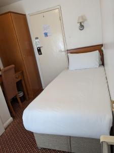 ein kleines Schlafzimmer mit einem weißen Bett in einem Zimmer in der Unterkunft The Tudor Hotel in Harrow