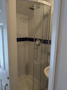 a shower with a glass door next to a sink at The Tudor Hotel in Harrow