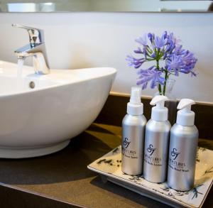 a bathroom with three bottles of soap and a sink at Supertubes Guesthouse in Jeffreys Bay +168 photos