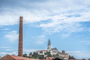 a building with a tall smoke stack and a church at Nitra Castle Suite - Modern Elegance & Serenity in Nitra