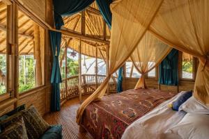 ein Schlafzimmer mit einem Himmelbett in einem Zimmer mit Fenstern in der Unterkunft Harmony House, Bamboo House with Pool view in Bringkit
