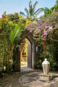 einen Torbogen mit einer Vase in einem Garten mit Blumen in der Unterkunft Harmony House, Bamboo House with Pool view in Bringkit