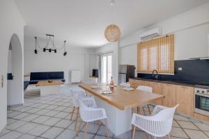 a kitchen with a wooden table and white chairs at Aegean Glory Suites in Ermoupoli