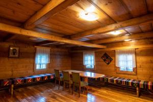 a dining room with a table and chairs and windows at Pensiunea Casa Bunicilor in Mănăstirea Humorului