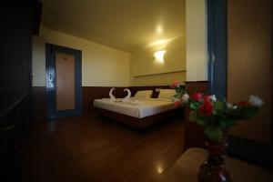 um quarto com uma cama e um vaso de flores em Jayaraj Residency em Kodaikanal