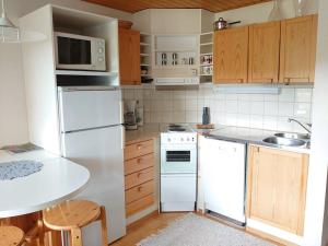 a kitchen with white appliances and wooden cabinets at Rivitalon huoneisto Tahkolla in Tahkovuori