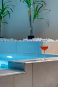 a glass of wine sitting on a counter next to a swimming pool at Aegean Glory Suites in Ermoupoli