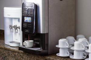 a coffee maker on a counter with cups and saucers at Belém Soft Hotel in Belém