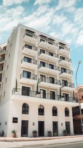 a large white building with balconies on a street at Kondo Hotel Allure in Budva