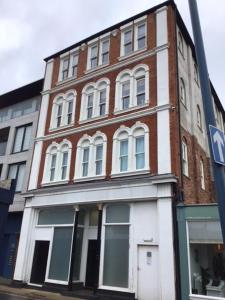 a brick building with white windows on a street at Stunning penthouse apartment in Teignmouth in Teignmouth