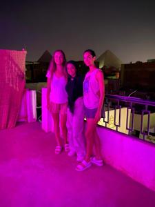 um grupo de três pessoas em pé na frente de luzes roxas em 2 Jana Pyramids view inn no Cairo