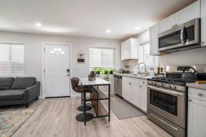 una cucina con armadi bianchi, tavolo e divano di Urban Oasis: San Diego Bungalow Escape a San Diego