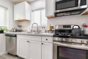 uma cozinha com armários brancos e um forno com placa de fogão em Urban Oasis: San Diego Bungalow Escape em San Diego
