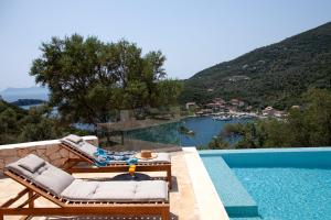 a pool with two lounge chairs and a view of the water at Villa Dara and Todd in Sivota