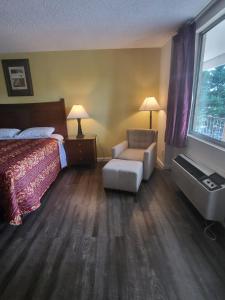 a hotel room with a bed and a chair and a window at America's Inn Williamsburg in Williamsburg