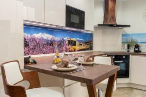 een keuken met een eettafel en een schilderij van een trein aan de muur bij Plaisir des pierres in Rivesaltes +12 foto's