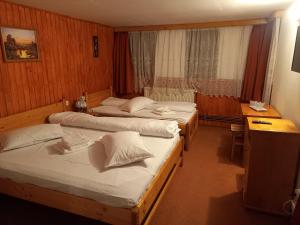 una camera d'albergo con 2 letti e una scrivania di Casa Ardeleană Cheia a Cheia