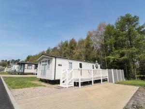 a small white trailer with a porch and a fence at Moon Stone in Morpeth