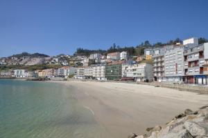 CASA MAR DE LUNA Playas en Raxo في راكسو: اطلالة على شاطئ فيه مباني وشقق