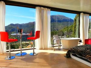 1 dormitorio con bañera y ventana grande en Stylish beautiful and exotic Oleandro glass Suite, en Casares