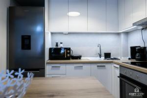 uma cozinha com armários brancos e um frigorífico preto em Cozyhome3 Navarinou em Tessalônica