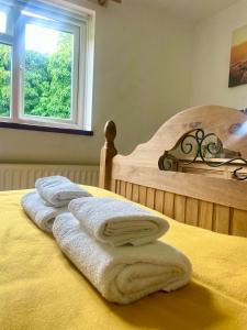 a bed with towels on it with a window at The Cottage On the Common in Tenbury