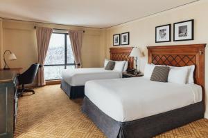 a hotel room with two beds and a desk at Fairmont Tremblant in Mont-Tremblant