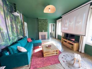un soggiorno con divano blu e grande schermo di Jungle Urbain- Sauna - Ciné - Hamac - Hyper centre ad Amiens