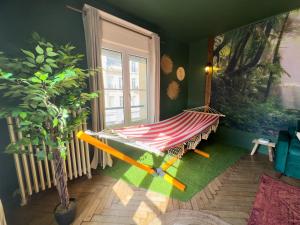 un'amaca in una stanza con una pianta e una finestra di Jungle Urbain- Sauna - Ciné - Hamac - Hyper centre ad Amiens