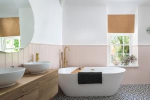 La salle de bains est pourvue de 2 lavabos blancs et d'une baignoire. dans l'établissement The Cors Country House, à Laugharne