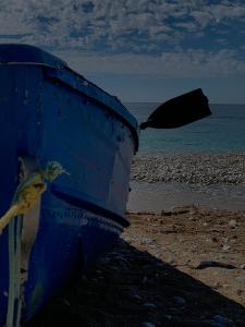 a blue boat on the beach with a bird flying at Vourtaréa Guesthouse in Himare