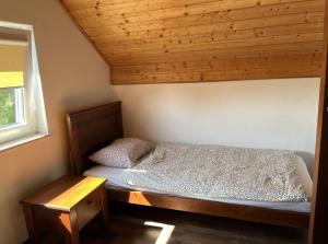 a small bed in a room with a wooden ceiling at Sekret Łeba Dom i Domki in Łeba