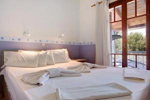 a bedroom with a white bed with towels on it at Areti Orfeas Apartment 7 in Vasilikos