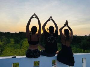 three girls sitting on a ledge doing yoga at sunset at Sigiri Sierra View Resort in Sigiriya