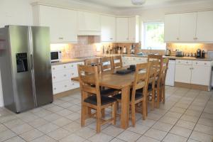 Il comprend une cuisine équipée d'une table en bois et d'un réfrigérateur. dans l'établissement Bramble Cottage - Luxury Holiday Cottage - 4 Beds 3 Baths - Parking - Beach 1 Mile - Fenced Child & Dog Friendly - EV Chrger, à Bude