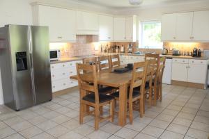 eine Küche mit Holztisch und Kühlschrank in der Unterkunft Bramble Cottage - Luxury Holiday Cottage - 4 Beds 3 Baths - Parking - Beach 1 Mile - Fenced Child & Dog Friendly - EV Chrger in Bude