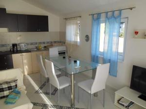 a kitchen with a glass table and white chairs at Karin Apartmani Hani in Gornji Karin