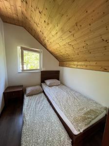 2 camas en un dormitorio con techo de madera en Sekret Łeba Dom i Domki, en Łeba
