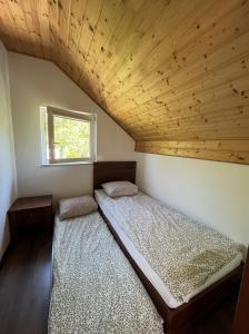 two beds in a bedroom with a wooden ceiling at Sekret Łeba Dom i Domki in Łeba