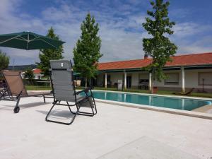 a pair of chairs and an umbrella next to a pool at Quinta Lourena - Casa do Caseiro in Covilhã
